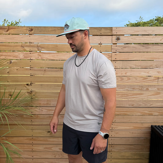 Salt SQD SqdDrift tee in Sea Mist with four-way stretch fabric, shown outdoors against a wooden fence.