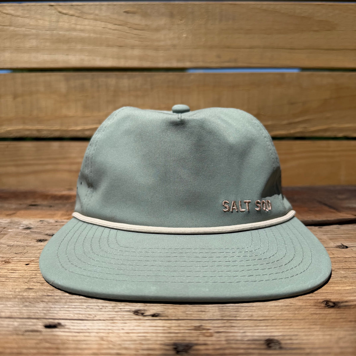 Salt SQD Coastal Core cap in Salt Sage with an embroidered logo and curved brim on a wooden surface.