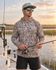 Man wearing a camouflage hooded shirt and cap, holding a fishing rod on a boat at sunset